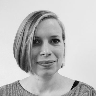 Iris Erkelens die in de camera kijkt met een glimlach en een kort boblijn kapsel tot haar kaak